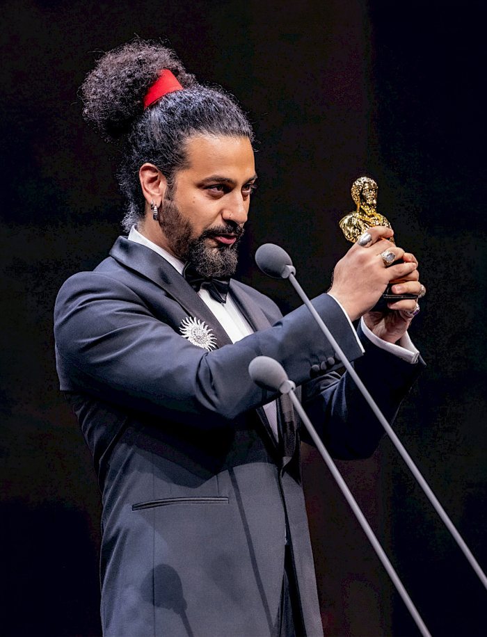 Mani Nickpour on stage holding an award