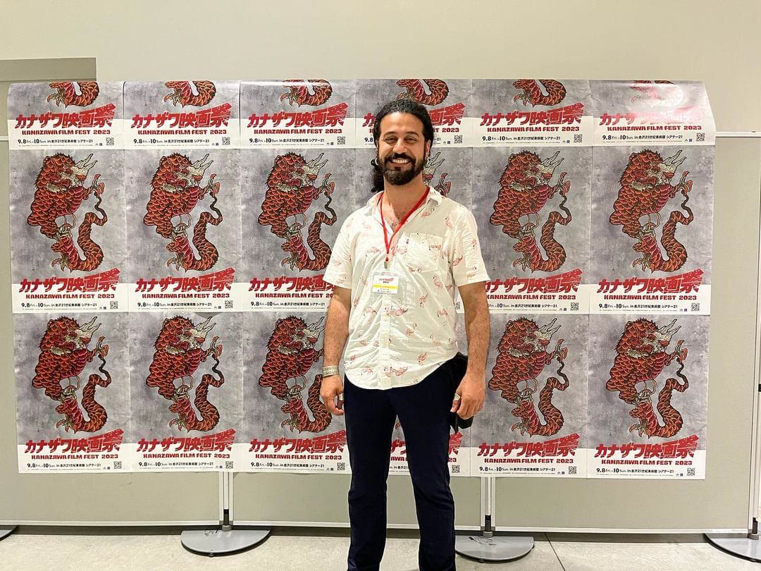 Mani Nickpour in front of the Kanazawa Film Festival 2023 posters